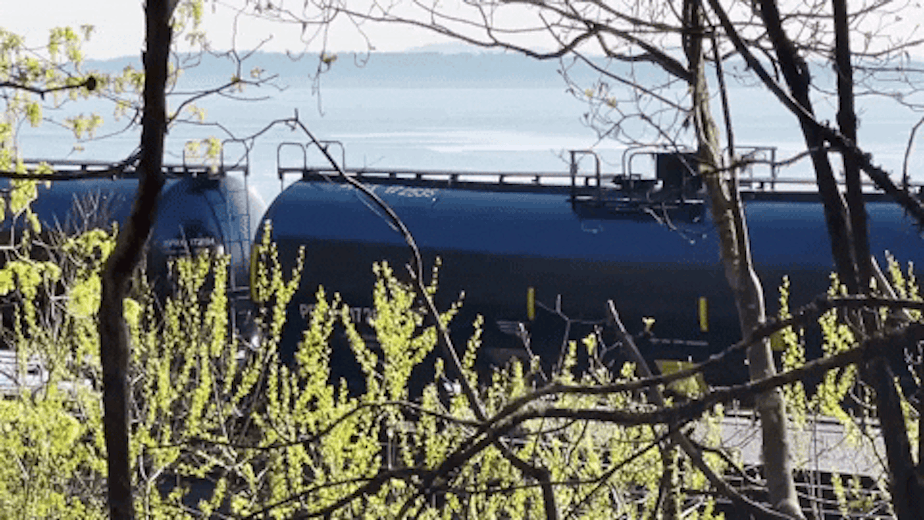 caption: An oil train rolls along Puget Sound in Shoreline, Washington, in May 2021.
