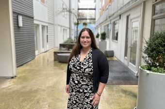 caption: Angela Rozmyn stands outside the Arete micro-apartments in Kirkland, Washington.
