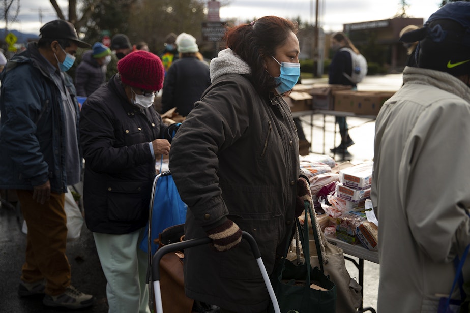 caption: Josefina Renteria, a volunteer and shopper, collects food during a weekly food share event on Saturday, Dec. 10, 2022, in Bellingham. Birchwood residents have been without a grocery store since 2016, when Albertsons bought Safeway.
