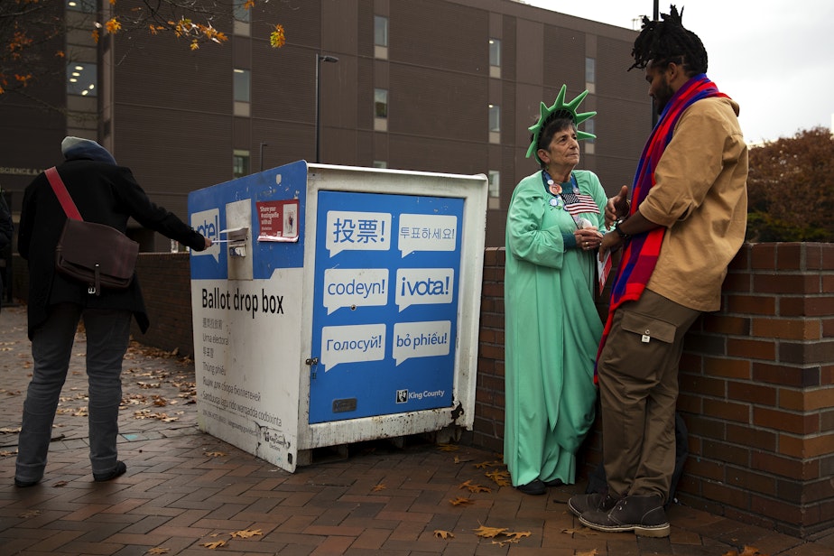 caption: Patti Gorman, dressed as lady liberty, talks with her former Seattle Central student, Afrikaan Sahra, right, as voters cast their ballots on Tuesday, November 5, 2024, outside of Seattle Central College in Capitol Hill. Sahra is voting for the first time after receiving U.S. citizenship.
