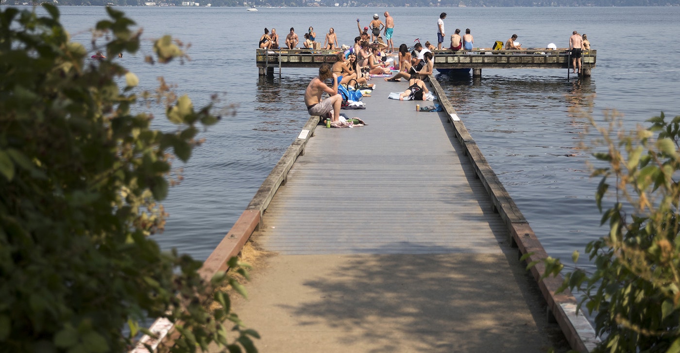 caption: A crowd gathers on a public dock on Monday, July 30, 2018, near Madrona Park in Seattle.