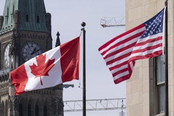 caption: The Canadian and U.S. flags are displayed on lamp posts in the downtown area, March 22, 2023, near Parliament Hill in Ottawa, Ontario.