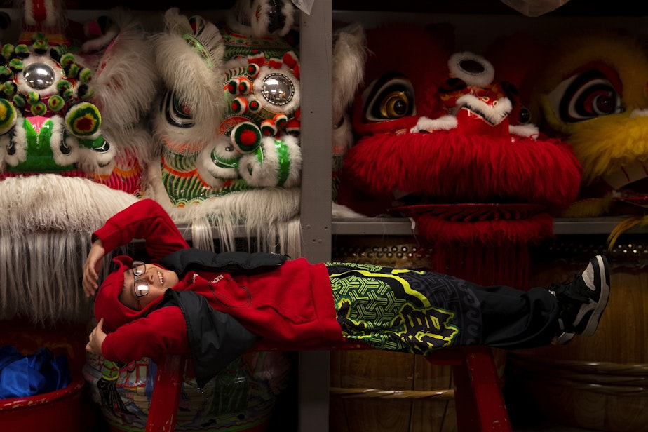caption: Kyle Nguyen, 7, rests on a bench as the Mak Fai Dragon and Lion dancers get ready for several performances ahead of the Lunar New Year celebration on Saturday, Feb. 4, 2023, in Seattle’s Chinatown-International District.