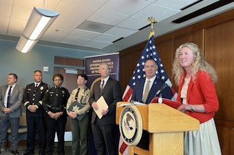 caption: U.S. Attorney Tessa Gorman and other law enforcement officials announced federal racketeering charges against two men accused of organizing home robberies targeting Asian Americans.