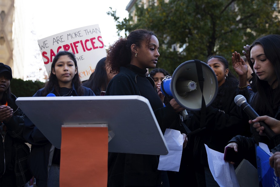 caption: Ingraham high school students, including senior Saron Gidey, center, take turns speaking into a megaphone to thousands of other Seattle students, during a rally demanding gun reform and safety on Monday, November 14, 2022, at Seattle City Hall. A deadly shooting took place at the school less than one week ago.