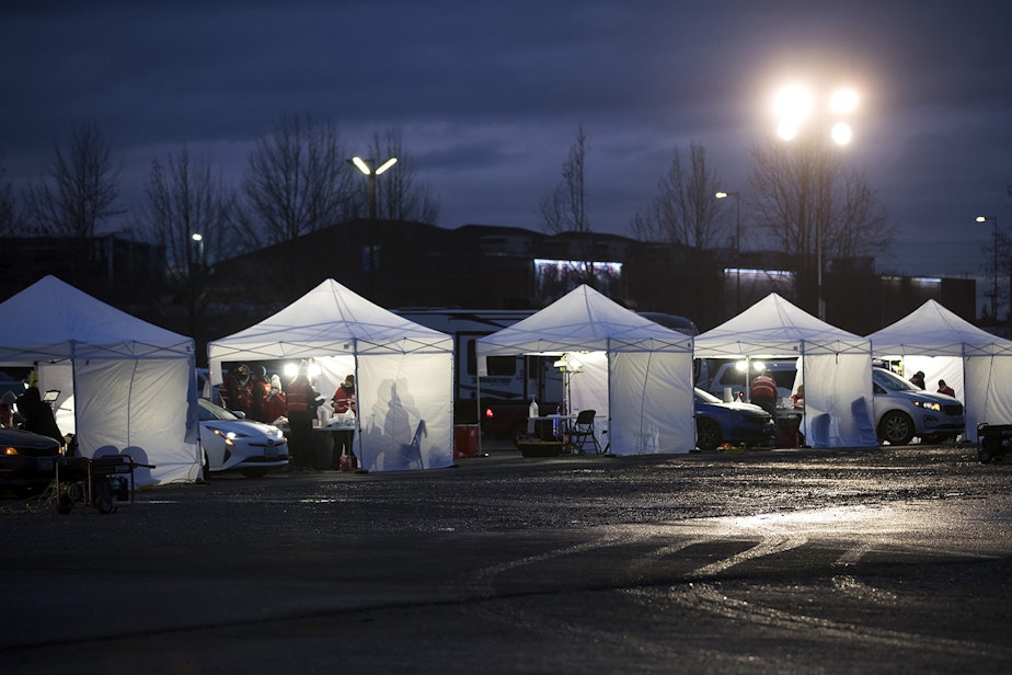 caption: A line of vaccine tents are lit up as the sun goes down on Thursday, January 28, 2021, during a free drive-thru Covid-19 vaccination clinic at the Washington State Fair Events Center in Puyallup. The clinic vaccinated approximately 2,000 people in phases 1A and 1B of the state’s vaccination plan on Thursday.