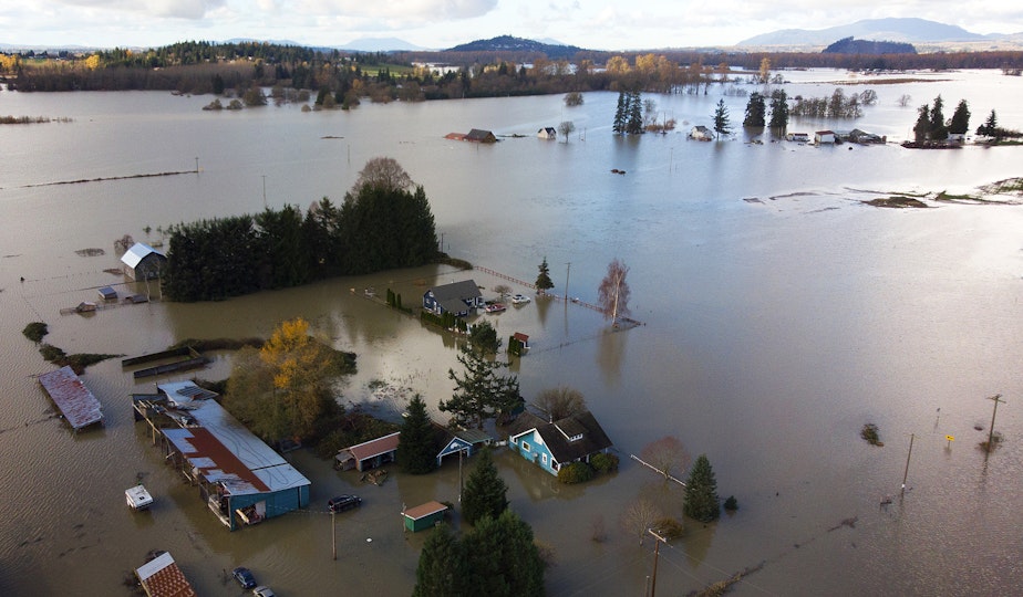 caption: Homes are shown surrounded by flood waters on Tuesday, November 16, 2021, east of Mount Vernon.