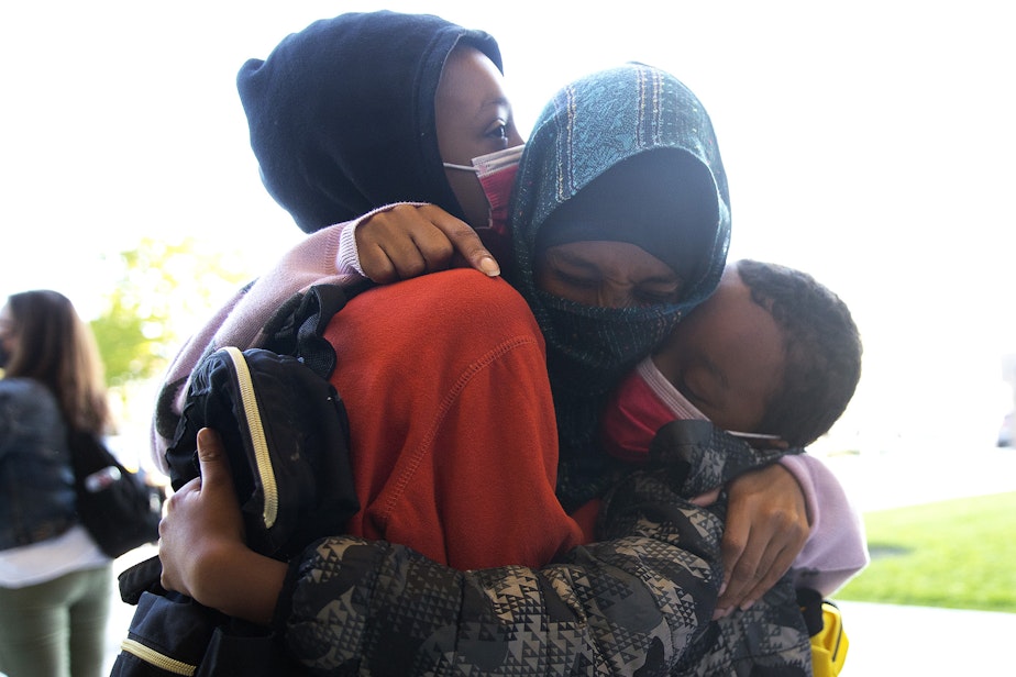 caption: Safia Hussein, center, hugs her sons, 4th-grade student Anwaar Boneya, left, and 2nd-grade student Sabir Boneya, right, before they head into their first day of school at Wing Luke Elementary School on Wednesday, September 1, 2021, along Kenyon Street in Seattle.