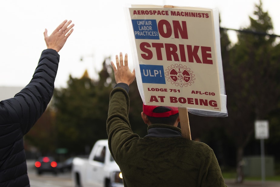 caption: Boeing machinists Gary Wong, right, and Andrey Grushke, left, wave to honking vehicles while striking on Wednesday, October 23, 2024, in Renton. Boeing Machinists vote Wednesday to accept or reject the latest contract offer.