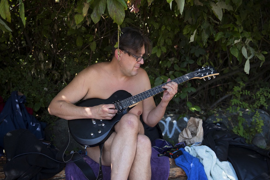caption: Dan O'Day plays guitar on Monday, August 27, 2018, at Denny Blaine Park in Seattle.