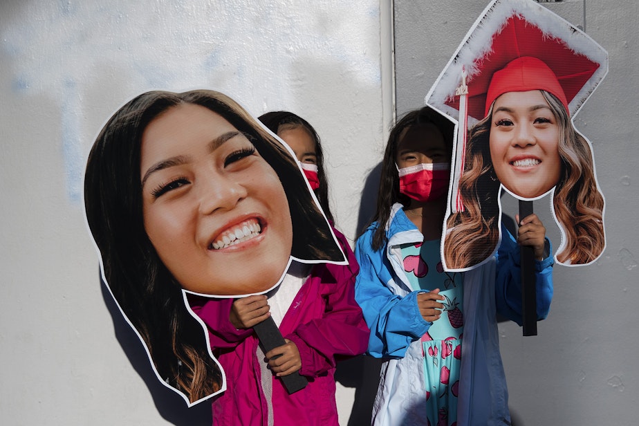 caption: Twin sisters from left, Kasey and Penelope Caldejon, hold images of their sisters, also twins, Isabella and Aaliyah Caldejon, ahead of the Cleveland Stem High School in-person graduation ceremony on Tuesday, June 15, 2021, at Memorial Stadium in Seattle.