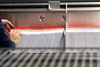 caption: FILE - This Nov. 7, 2018, file photo shows an election worker stacking ballots into a sorting machine at the King County Elections office in Renton, Wash. 