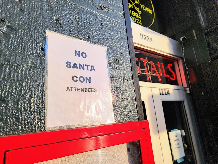 caption: A sign outside Diller Room bar that reads, 'NO SANTA CON ATTENDEES' on Dec. 7, 2024.