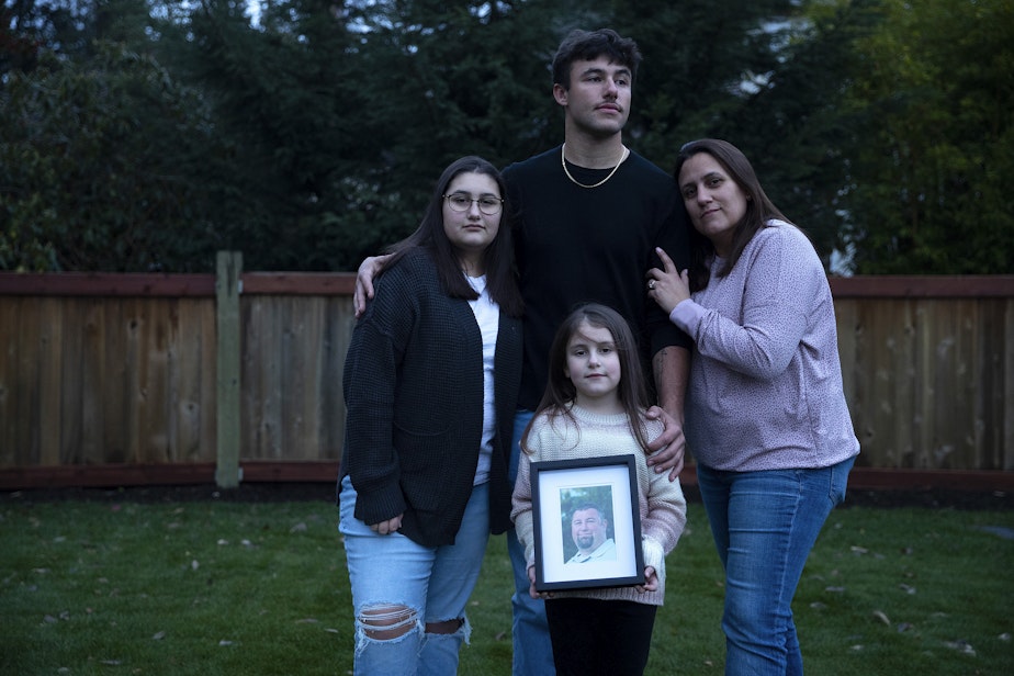 caption: Christy Maricle, right, stands for a portrait with her three children, Cadence, 20, Kaitlyn 13, Caileigh, 7, holding a portrait of their father, Kurt, on Thursday, December 9, 2022,at their home in Puyallup. Kurt Mrsny died of Covid in September of 2021.