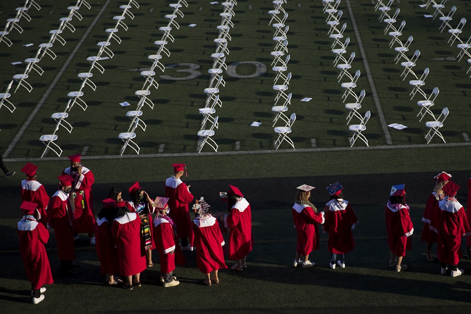 caption: Cleveland Stem High School seniors line up before taking their seats ahead of the in-person commencement ceremony on Tuesday, June 15, 2021, at Memorial Stadium in Seattle.