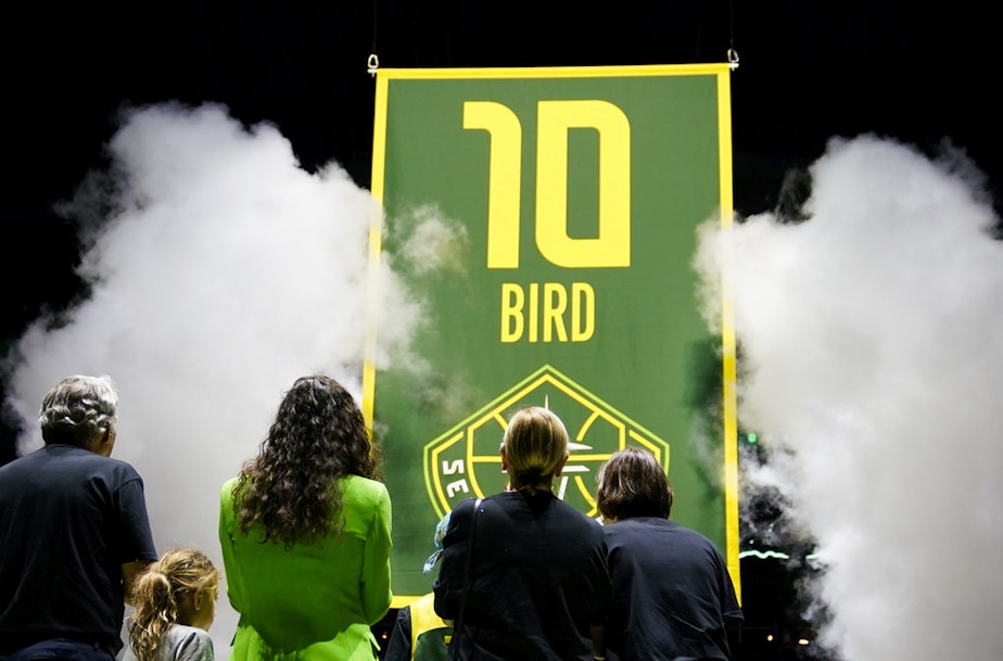 caption: Former Seattle Storm guard Sue Bird, in green, stands with her family as her jersey number is lifted into the rafters during a ceremony following a WNBA basketball game between the Storm and the Washington Mystics, Sunday, June 11, 2023, in Seattle.