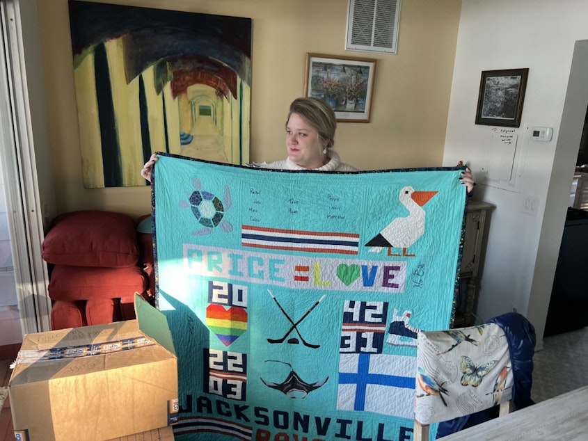 caption: Emily Rath, a romance author who just moved to Washington state this month, packed fan art and this fan-sewn quilt with references to her novels.