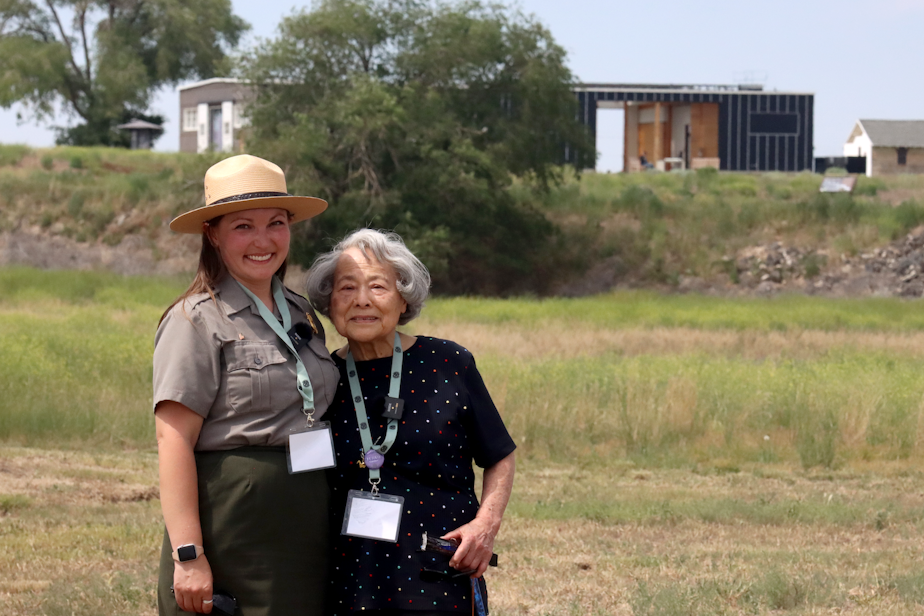 caption: Kelsea Larsen (left) with her grandmother, Fujiko Gardner (right), a survivor of Minidoka prison camp in rural Idaho. In the distance is the visitor's center with a museum about the camps.